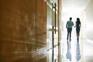 Two people talking as they walk down a hallway