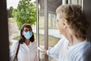 Senior woman opening the door for a health care worker