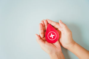 red blood shape in human's hand for world blood donor day and save life concept, blood donation, emergency case