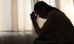 Person having depression sitting alone in bedroom dark corner.