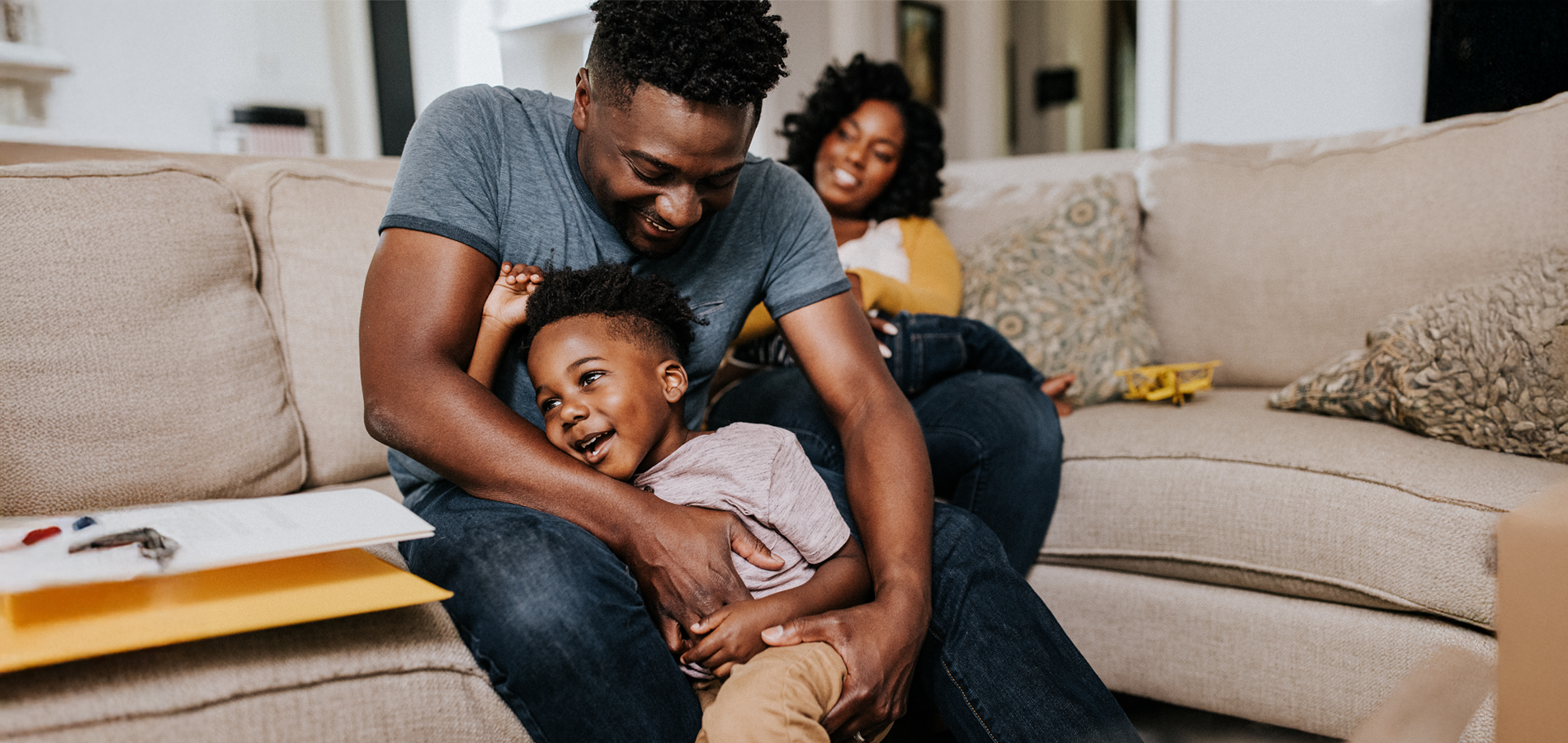 image of father holding happy child with wife in the background